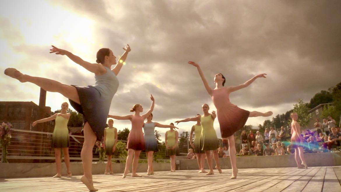 Ballet Dancers dressed in flowing dresses performing arabesques against a cloudy sky